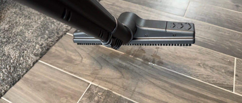 Polti Vaporetto Lecoaspira über einem Fliesenboden leicht in der Luft hängend, darunter ein Wasserfleck