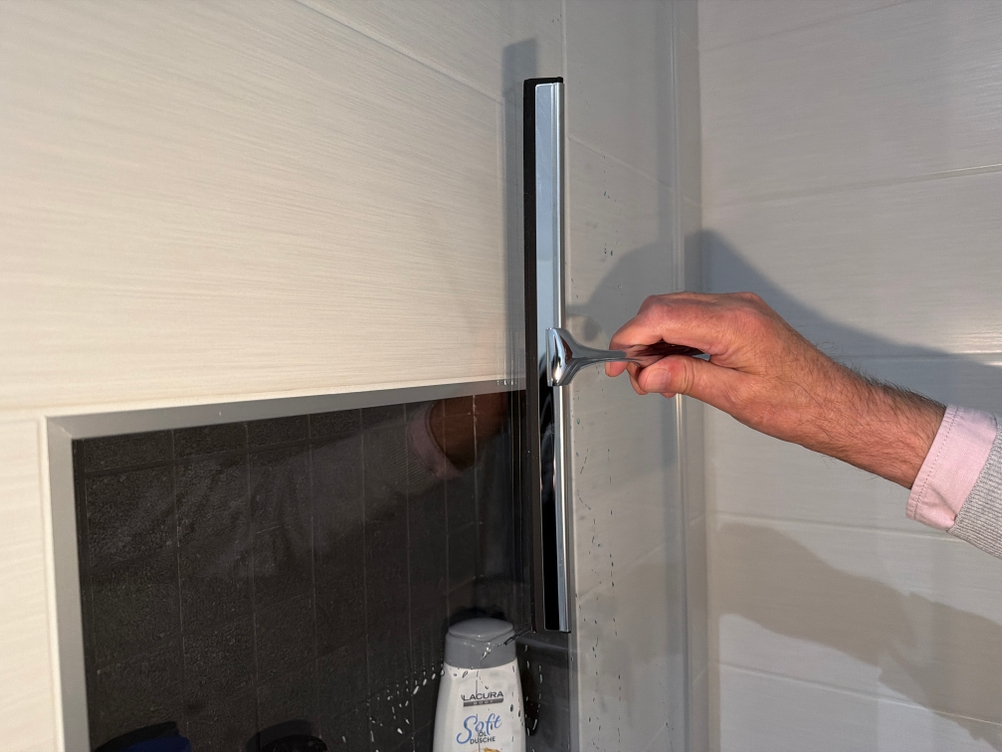 Mit dem Ponsey-Badwischer wird eine Glastür abgezogen