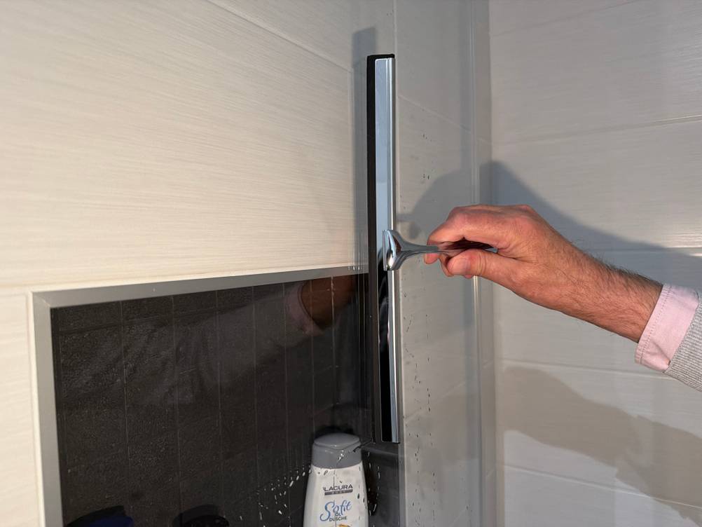 Mit dem Ponsey-Badwischer wird eine Glastür abgezogen