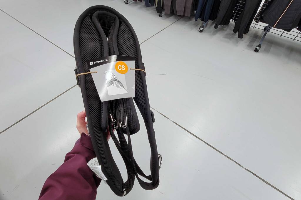 Longiergurt-Test: Eine Hand hält einen getesteten Fouganza Longiergurts vor einen hellen Hintergrund.