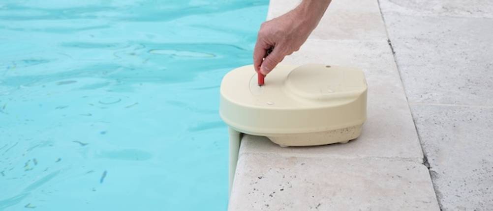 Funktionen des Pool-Alarms getestet: Eine Hand bedient den Pool-Alarm am Rand eines Swimming-Pools.