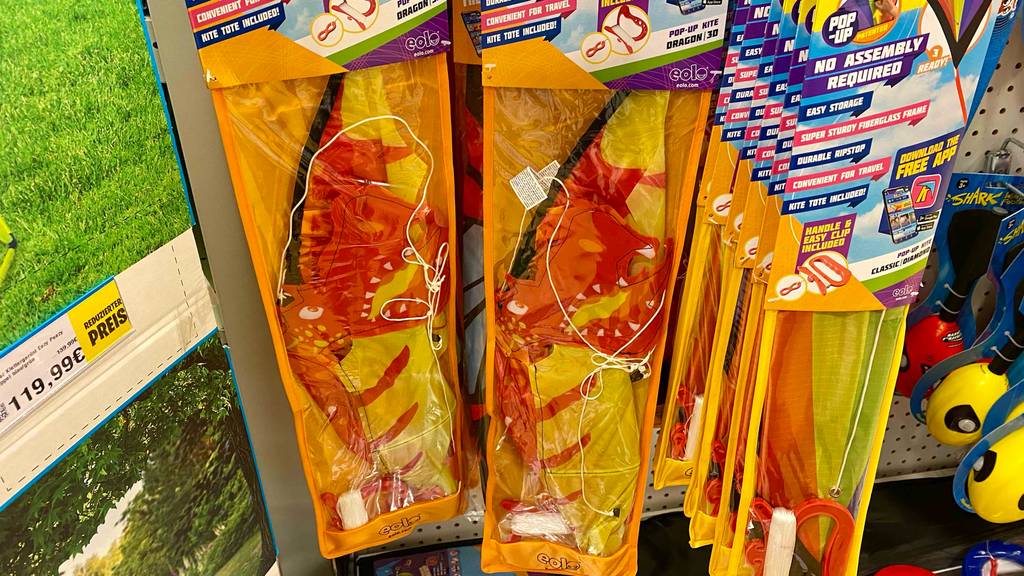 Im Test: Mehrere verpackte Kinderdrachen hängen neben- und hintereinander in einem Regal.