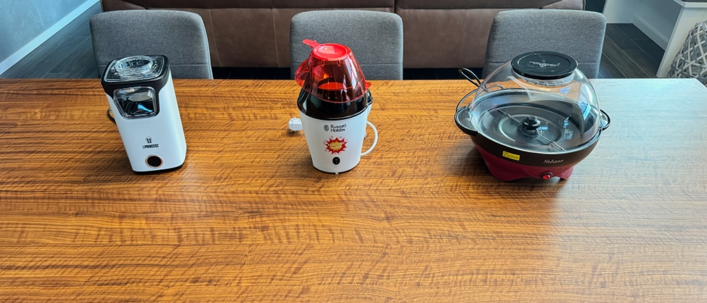 Drei Popcornmaschinen stehen auf einem Holztisch