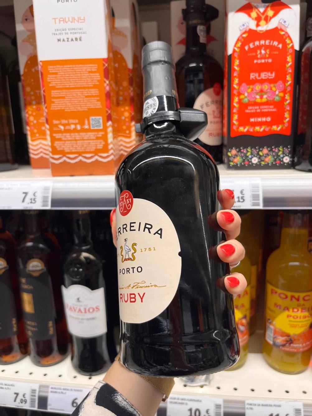 Portwein getestet: Eine Hand hält eine Flasche Portwein seitlich vor ein Regal.