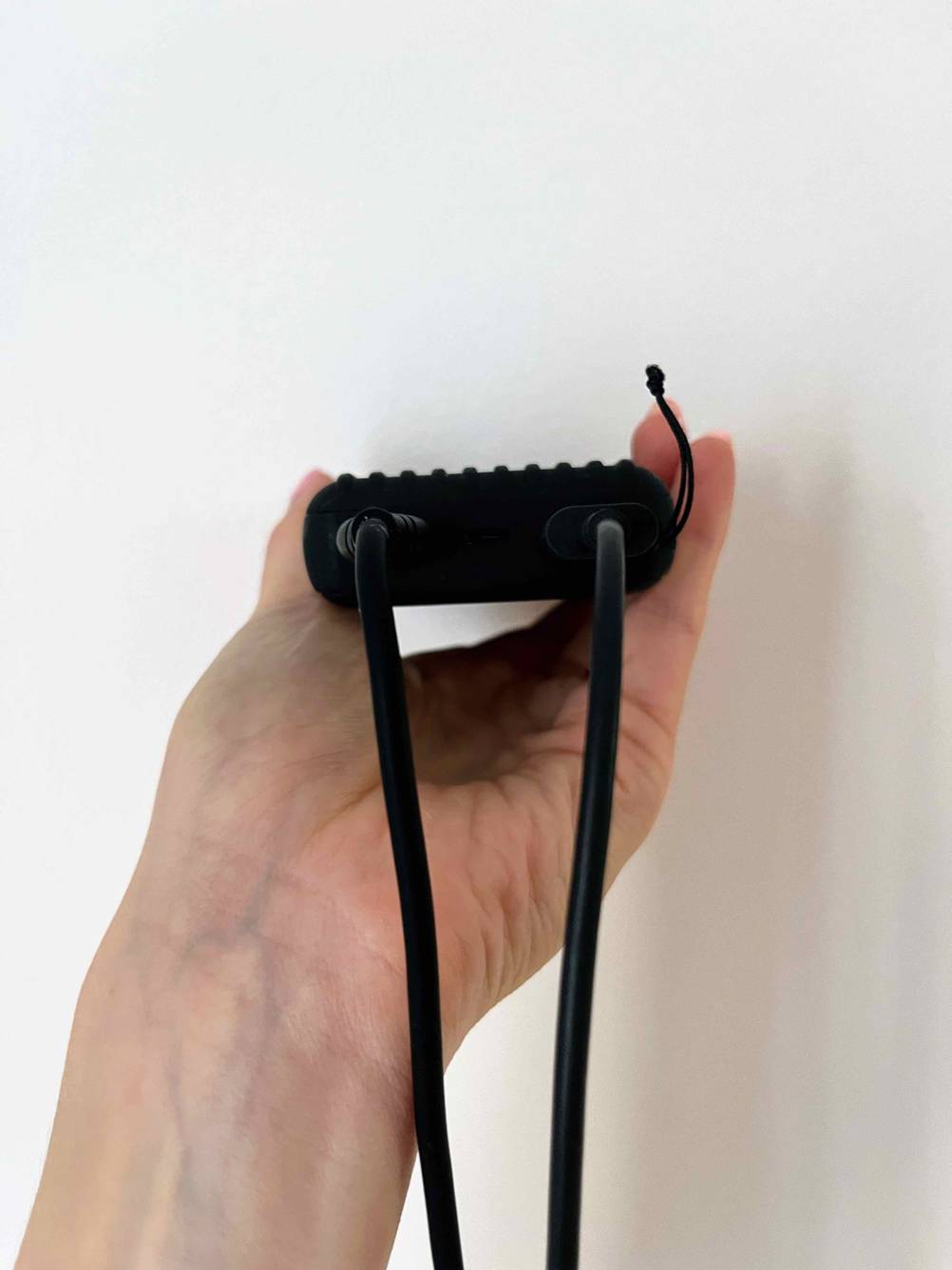 Im Test: Eine Hand hält die Powerbank 10.000 mAh mit den Anschlüssen nach vorne vor eine helle Wand.