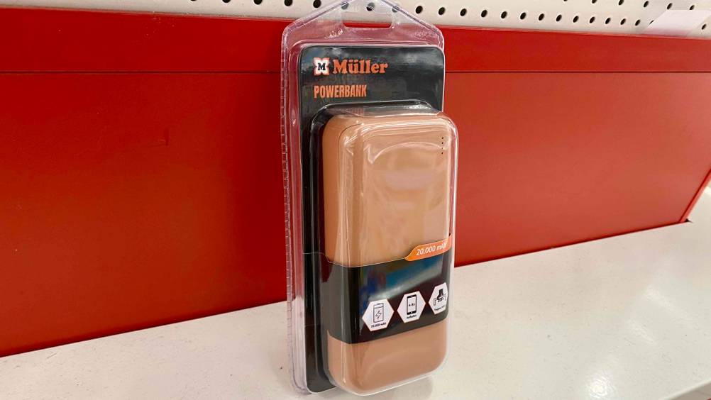 Eine transparent verpackte Powerbank 20.000 mAh im Test schräg von der Seite vor einer roten Wand.