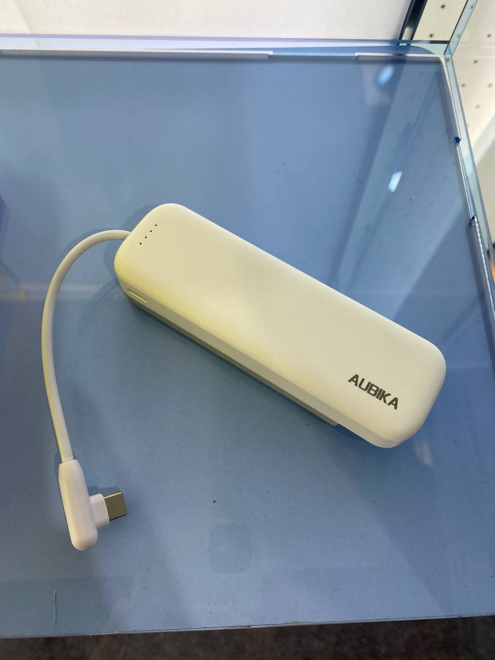 Powerbank getestet: Ein Gerät mit Kabel auf einer blauen Fläche von oben.