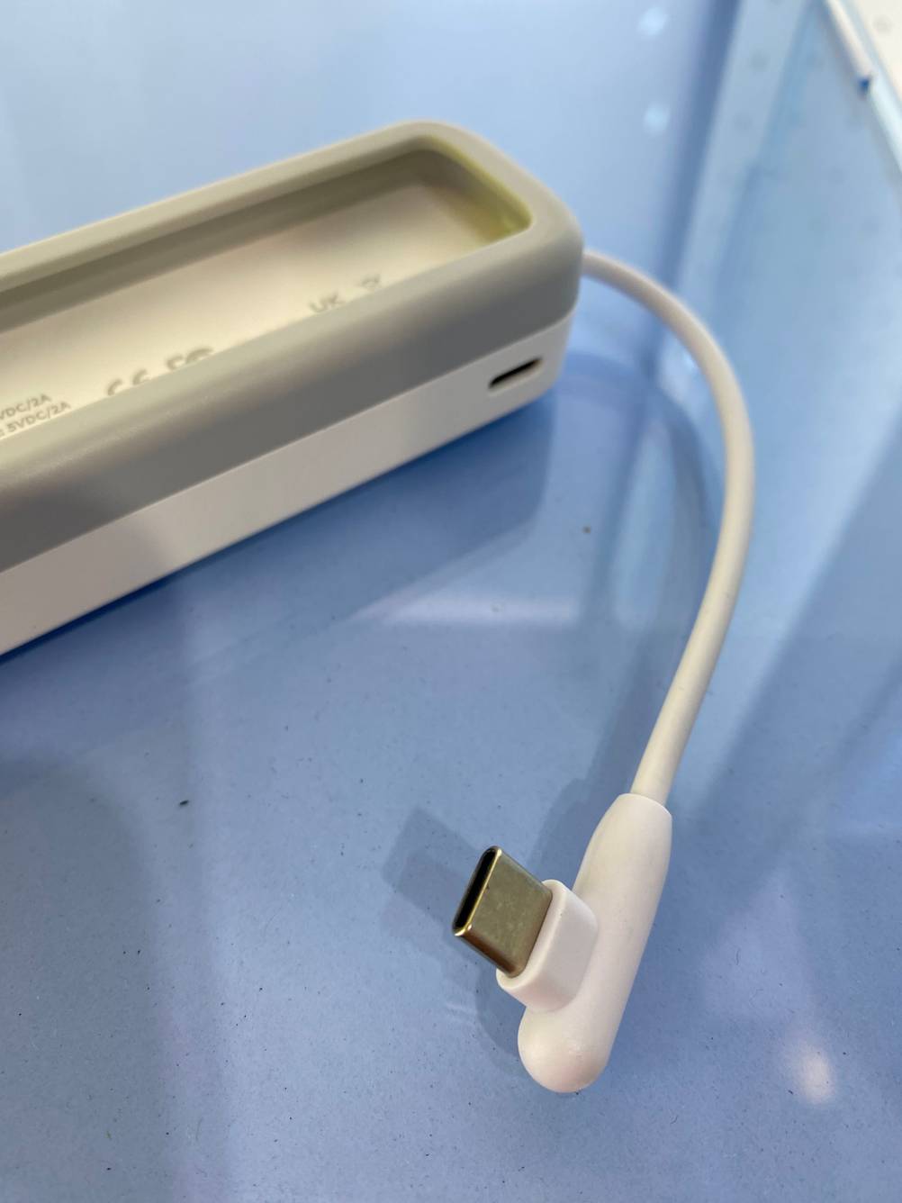 Nahaufnahme des Steckers einer getesteten Powerbank auf einer blauen Fläche.
