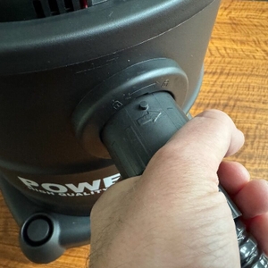 Eine Hand befestigt den Schlauch am Powerplus pow X308