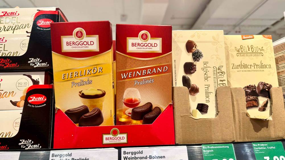 Mehrere Packungen der Pralinen mit Alkohol im Test in einem Verkaufsregal neben anderen Produkten.