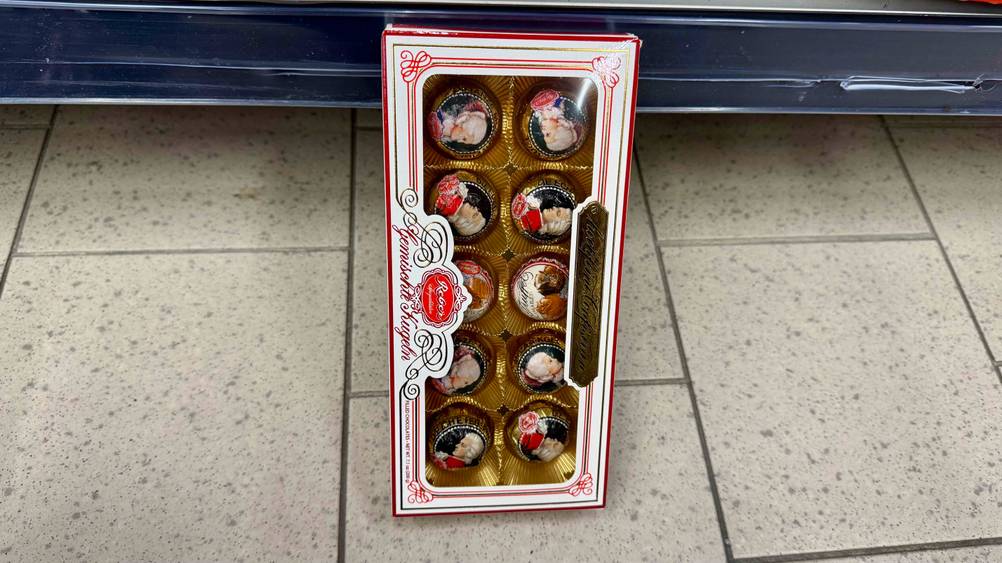 An einem Regal lehnt eine Packung der getesteten Pralinen.