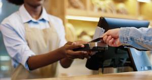 Eine Person zahlt in einem Geschäft mit einer aufladbaren Kreditkarte.