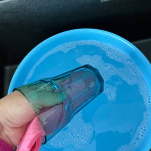 Eine Hand spült ein Glas mit einem Spüllappen aus.