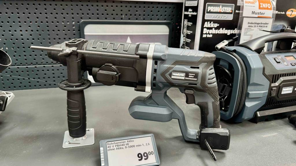 Der getestete Akku-Bohrhammer in Schwarz-Grau ist ohne Akku ist hinter seinem Preisschild (99 Euro) in einem Baumarkt ausgestellt.