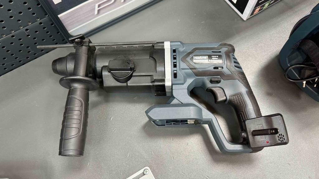 Akku-Bohrhammer im Test: Ein schwarz-graues Modell ohne Akku liegt auf einer grauen Oberfläche.