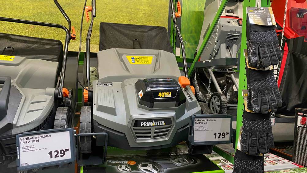 Akku-Vertikutierer getestet: Ein Gerät zwischen anderen Produkten in einem Verkaufsregal mit Preisangaben.