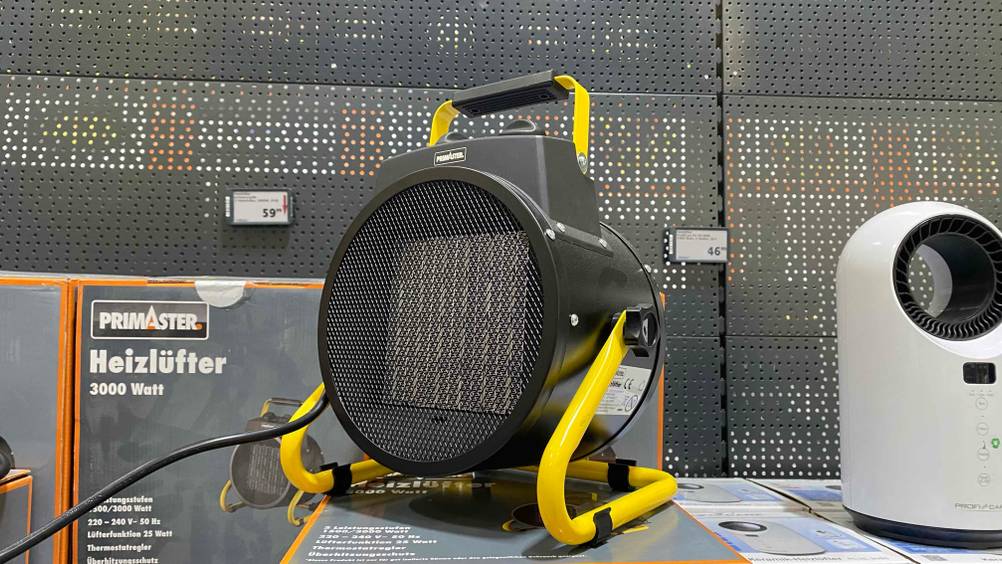 Heizlüfter 3000 Watt getestet: Ein Gerät von der Seite vor einem dunklen Lochblech mit Preisangaben.