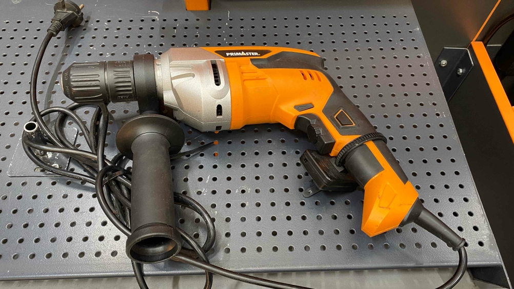 Im Test: Eine Schlagbohrmaschine auf einem dunklen Lochblech liegend.