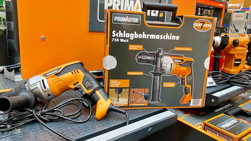 Schlagbohrmaschine-Test: Ein Gerät neben seiner Originalverpackung mit Infografik.