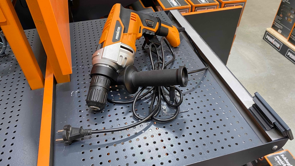 Schlagbohrmaschine getestet: Ein Gerät von schräg oben auf einem dunklen Lochblech liegend.