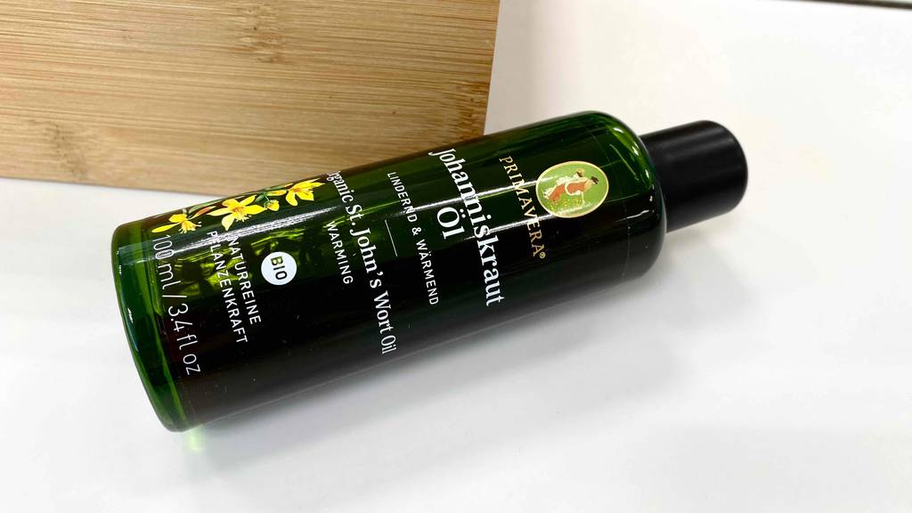 Flasche eines getesteten Johanniskrautöls liegt auf einem hellen Untergrund.
