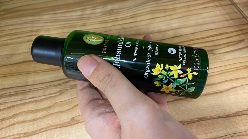 Eine Flasche Johanniskrautöl liegt zum Testen quer in einer Hand.