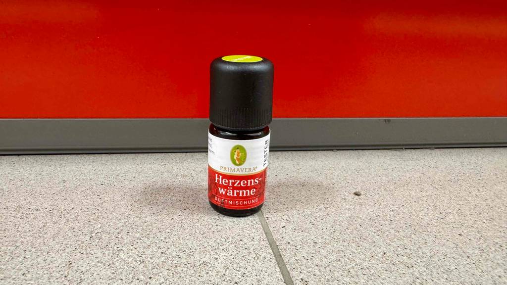 Ein Fläschchen getestete Primavera-Öle steht vor einer roten Wand.