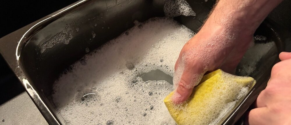 Eine Hand reinigt den Behälter der Princess 185000 mit einem Lappen