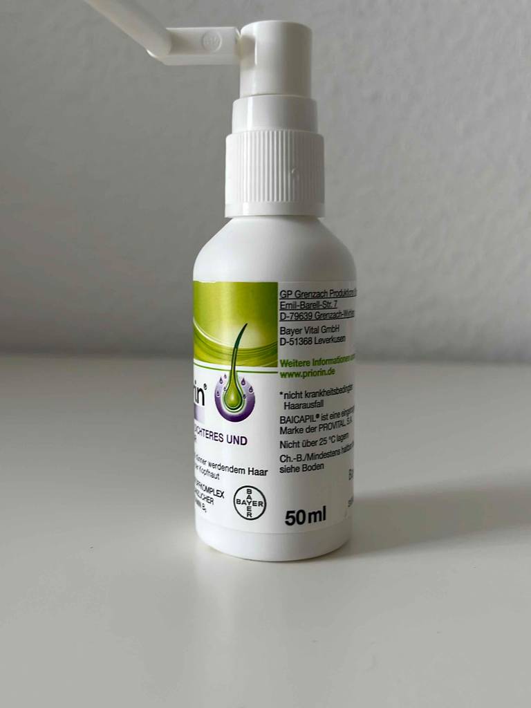Eine 50-ml-Dosierflasche mit getestetem Haarwasser steht auf einer weißen Oberfläche.