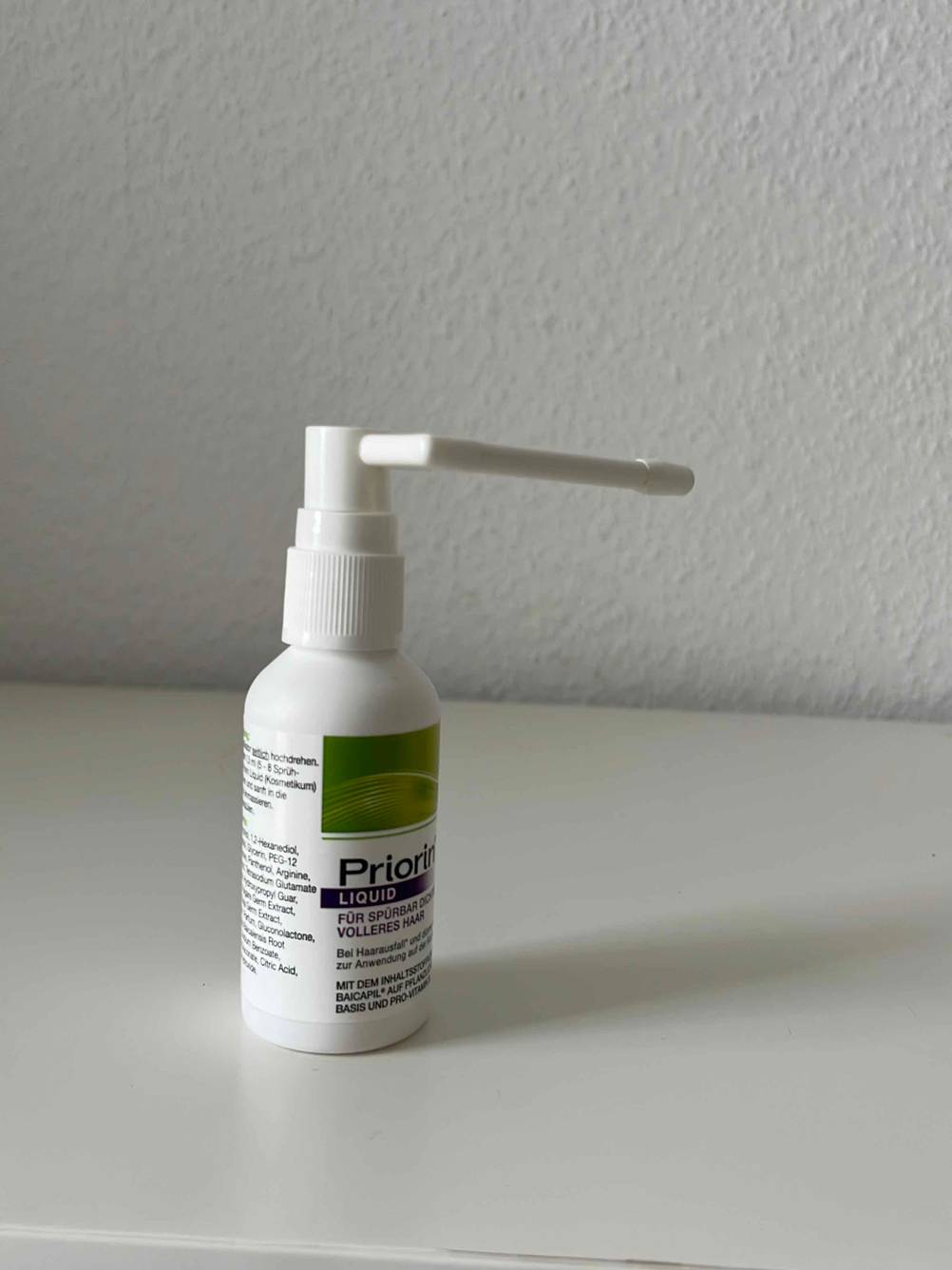 Haarwasser-Test: Gesamtansicht der Sprühflasche mit Haarwasser der Marke Priorin inklusive Sprüh-Dosier-Vorrichtung vor hellem Hintergrund.