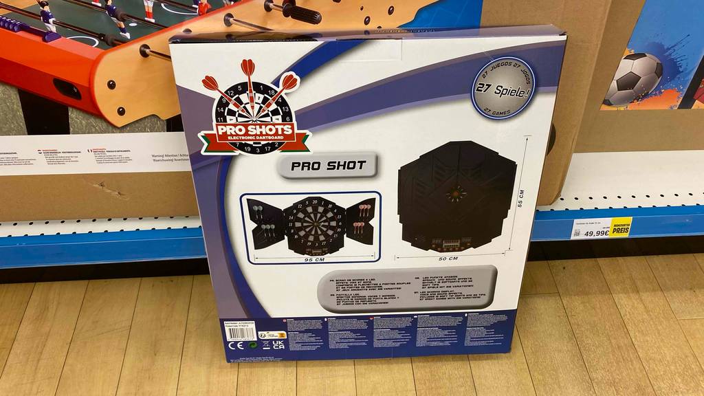 Dartscheibe im Test: Rückseite einer Originalverpackung, die vor einem Regal steht.