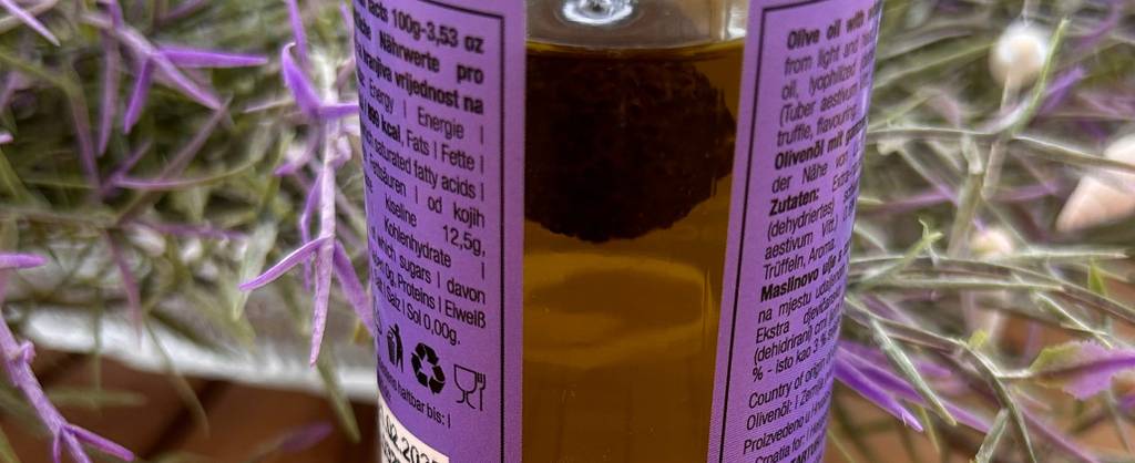 Nahaufnahme eines im Öl eingelegten schwarzen Trüffels, der sich in der Flasche eines getesteten Trüffelöls befindet.