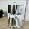 Die Melitta Look V Perfection steht vollständig aufgebaut auf einer Arbeitsfläche. Die Maschine hat eine Edelstahl-Thermoskanne.