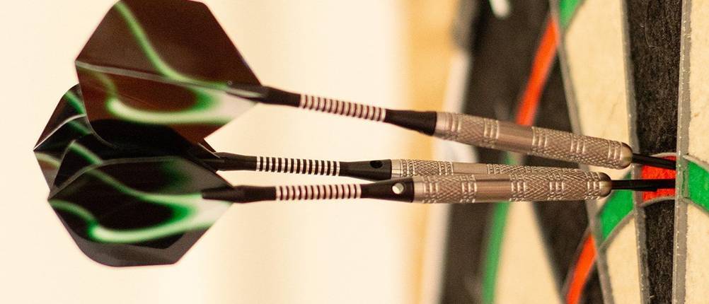 Dartpfeile im Test: drei Dartpfeile, die zielgenau in einer Dartscheibe stecken