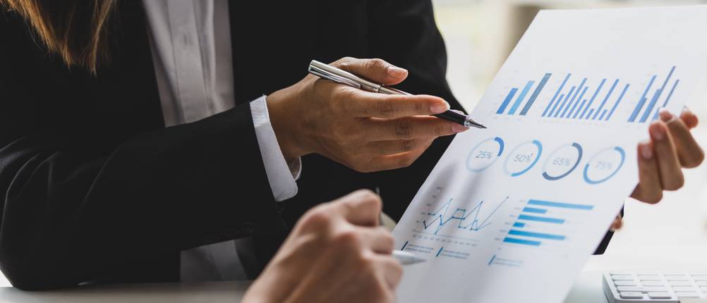 Online-Banking-Software-Test: Zwei Personen betrachten gemeinsam ein Blatt Papier mit grafischen Darstellungen von Finanzen.