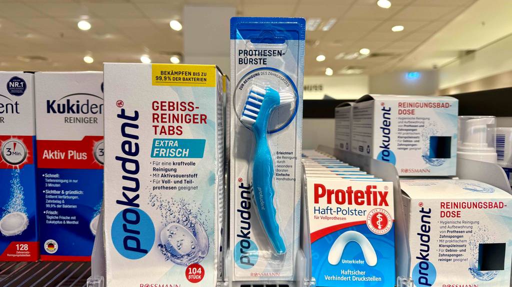 Eine getestete Prothesenbürste steht inklusive der Verpackung neben weiteren Prothesen-Pflegeprodukten auf einem Verkaufsregal.
