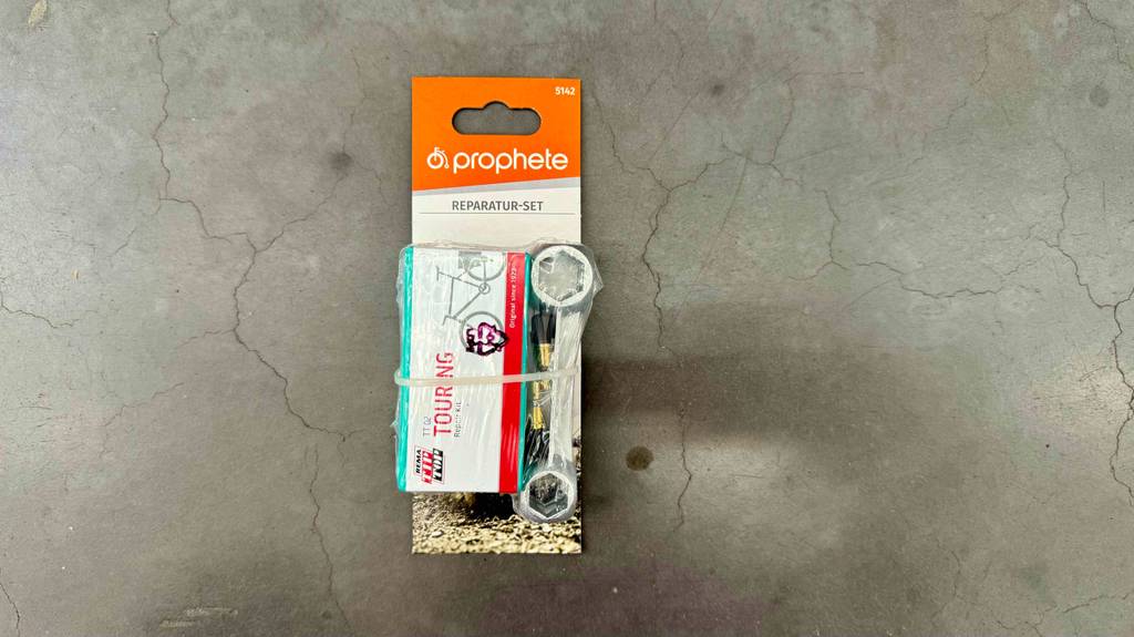 Im Test: Ein Fahrrad-Reparaturset liegt in einem Kartonblister verpackt auf einem Betonboden.