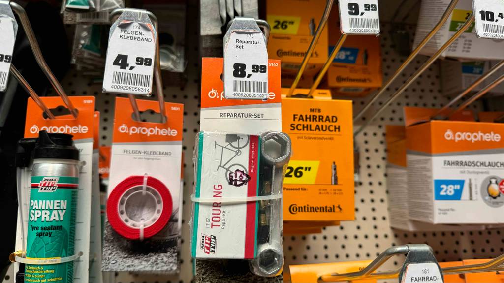 Fahrrad-Reparaturset im Test: Mehrere verpackte Sets hängen zwischen anderen Fahrradprodukten in einem Regal.