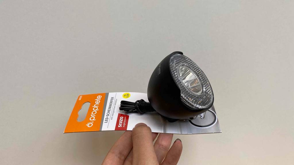 Im Test: Hand hält eine Fahrradlampe vor weißer Wand.