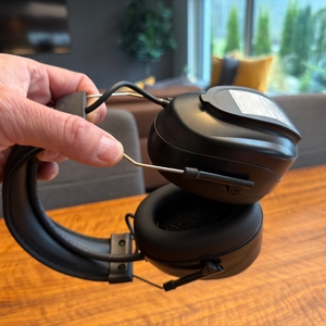 Eine Hand verlängert den Kopfbügel des Protear E8830BTDAB+.