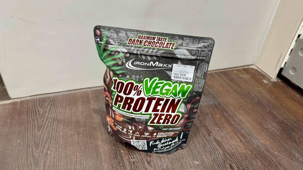 Eine Packung Schoko-Proteinpulver im Test auf einem Holzboden.