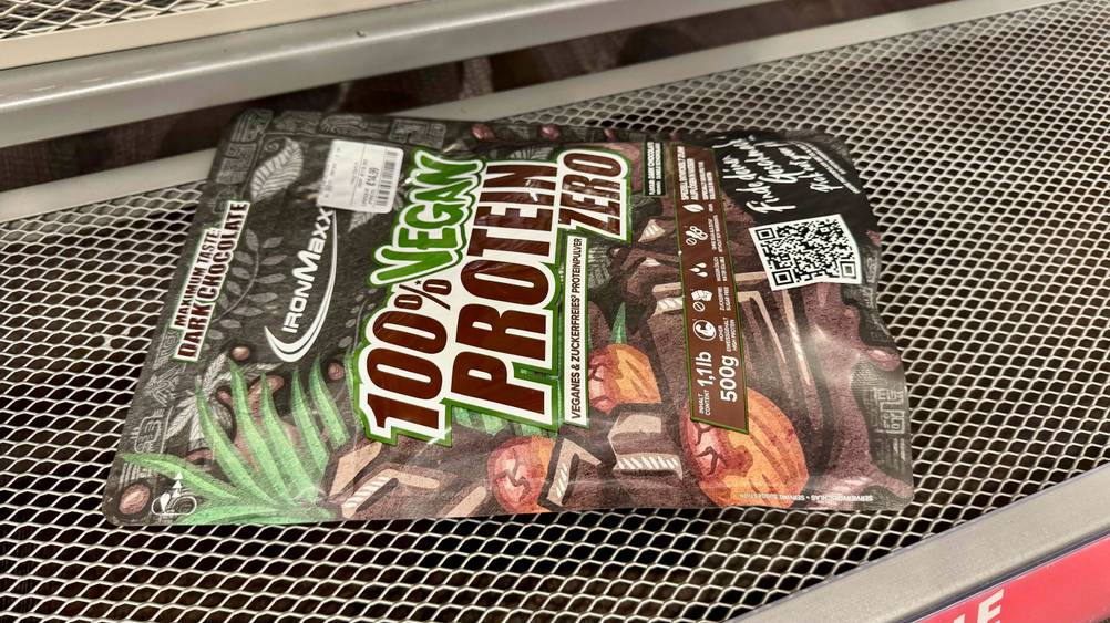 Getestet: Eine Packung Schoko-Proteinpulver horizontal auf einem Gitter liegend.