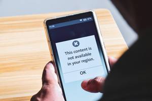 Proxy-Services im Test: Eine Person hält ein Smartphone in der Hand, auf dem ein Inhalt aufgrund einer Geo-Beschränkung nicht verfügbar ist.