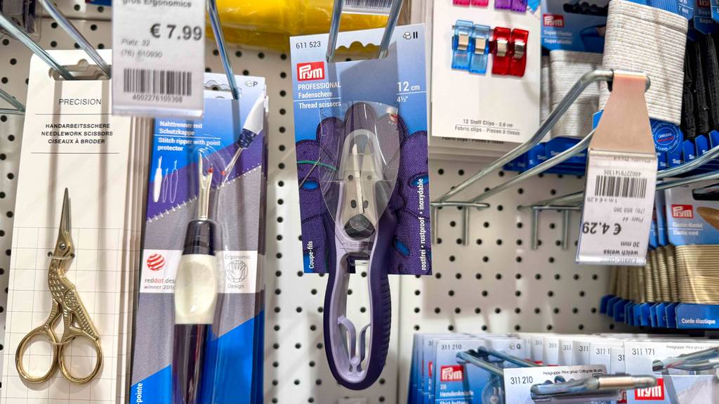 Im Test: Eine Fadenschere hängt zwischen anderen Nähprodukten in einem Hängeregal.