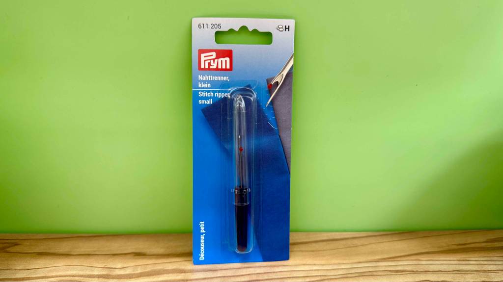 Ein Nahttrenner lehnt in Originalverpackung zum testen an eine grüne Wand.