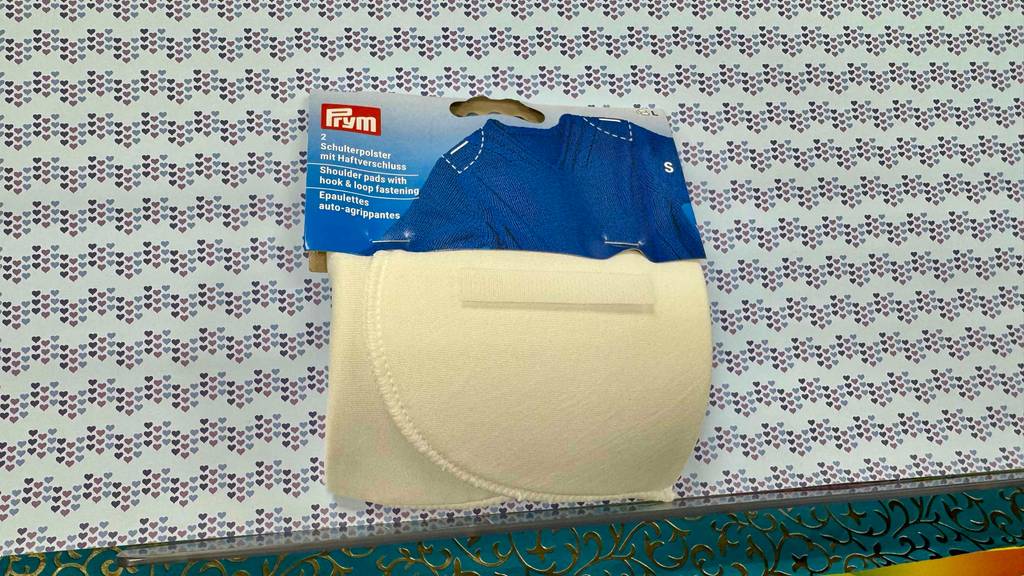 Ein 2er Pack Schulterpolster liegt zum testen auf einer Fläche mit vielen kleinen Herzen.
