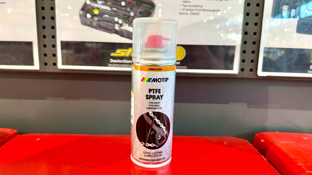 Auf einem roten Boden steht ein PTFE-Spray im Test.
