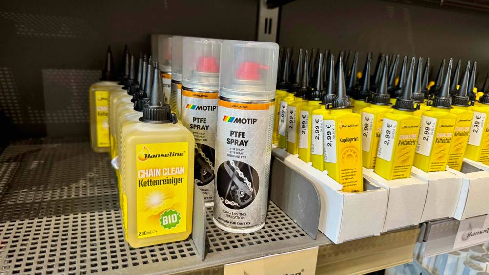 Mehrere Dosen des PTFE-Spray im Test in einem Regal neben anderen Produkten.