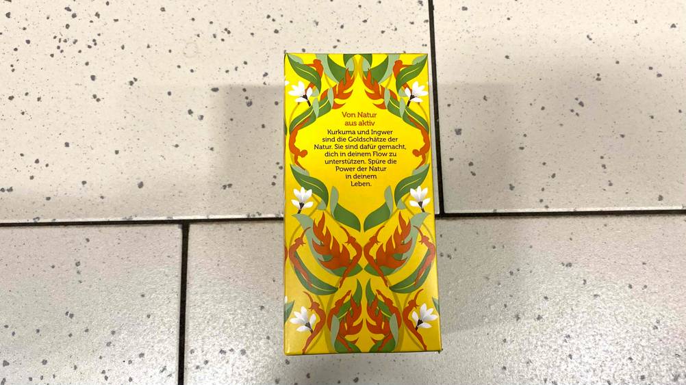 Kurkuma-Tee im Test: Rückseite einer Originalverpackung, die auf hellen Fliesen liegt.