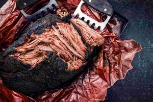 Ein großes Stück gegrilltes Rindfleisch neben zwei Fleischkrallen